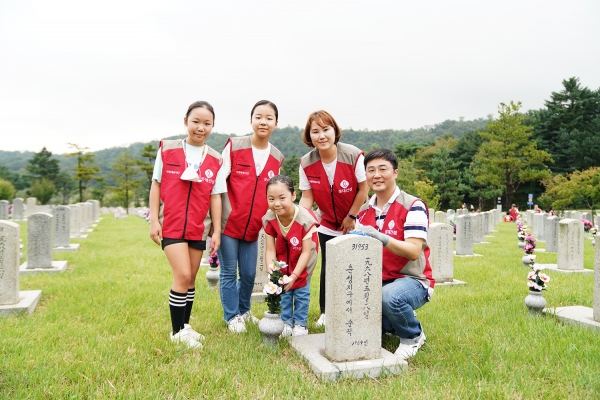 △롯데건설 임직원과 가족들이 자매결연 묘역에서 봉사활동 후 기념촬영을 하고 있다./제공=롯데건설