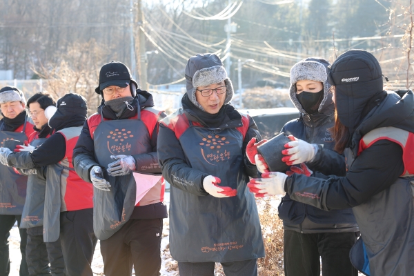 △박현철 롯데건설 부회장(오른쪽 3번째)과 배우 정애리(오른쪽 2번째)가 임직원들과 함께 연탄을 나르고 있다./제공=롯데건설